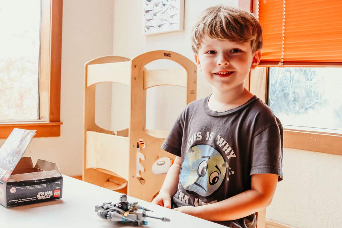 child sitting at a table with a Mandalorian lego N-1 starfighter microfighter