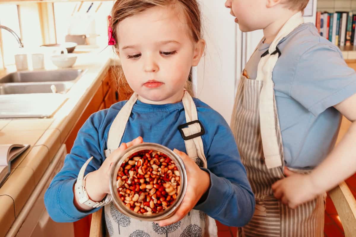 child pouring Sea Island Red Peas from Anson Mills into a Made In saucier