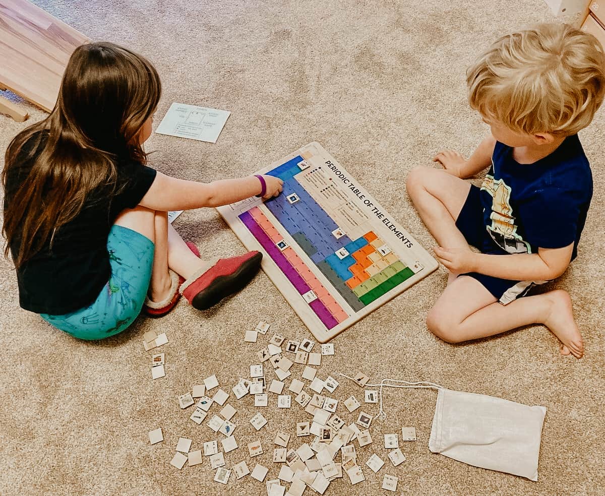 Child placing tiles on Mirus Toys Periodic Table of Elements Puzzle for exploring the history of the universe.