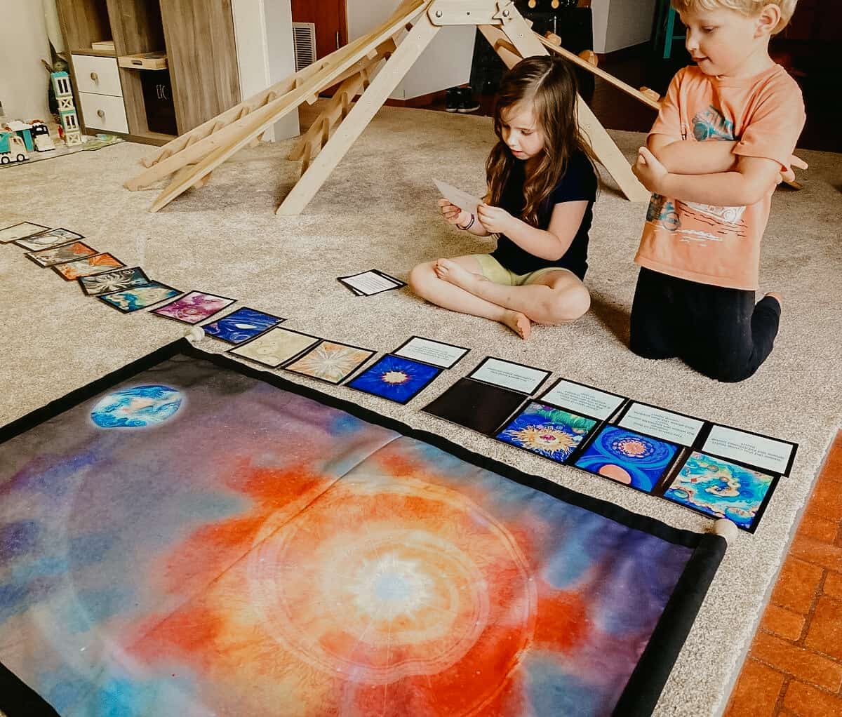 Montessori kids using Waseca Biomes Cosmic Story Mat in homeschool to explore the history of the universe