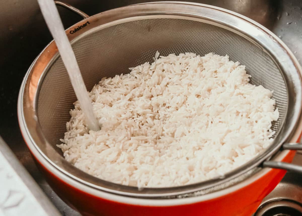 water running over rice in a fine-mesh strainer