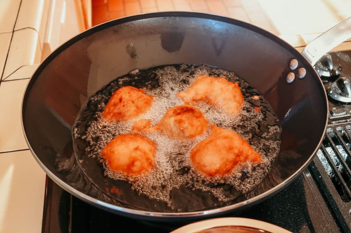 drop biscuits frying in oil in a blue carbon steel wok