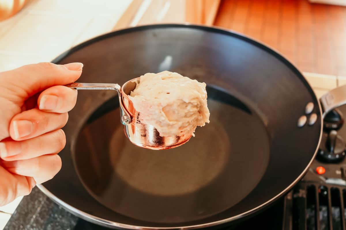 a measuring cup with drop biscuit dough inside and a wok in the background