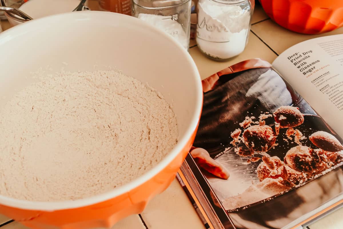 dry ingredients for making drop biscuits next to Still We Rise cookbook open to the drop biscuits recipe